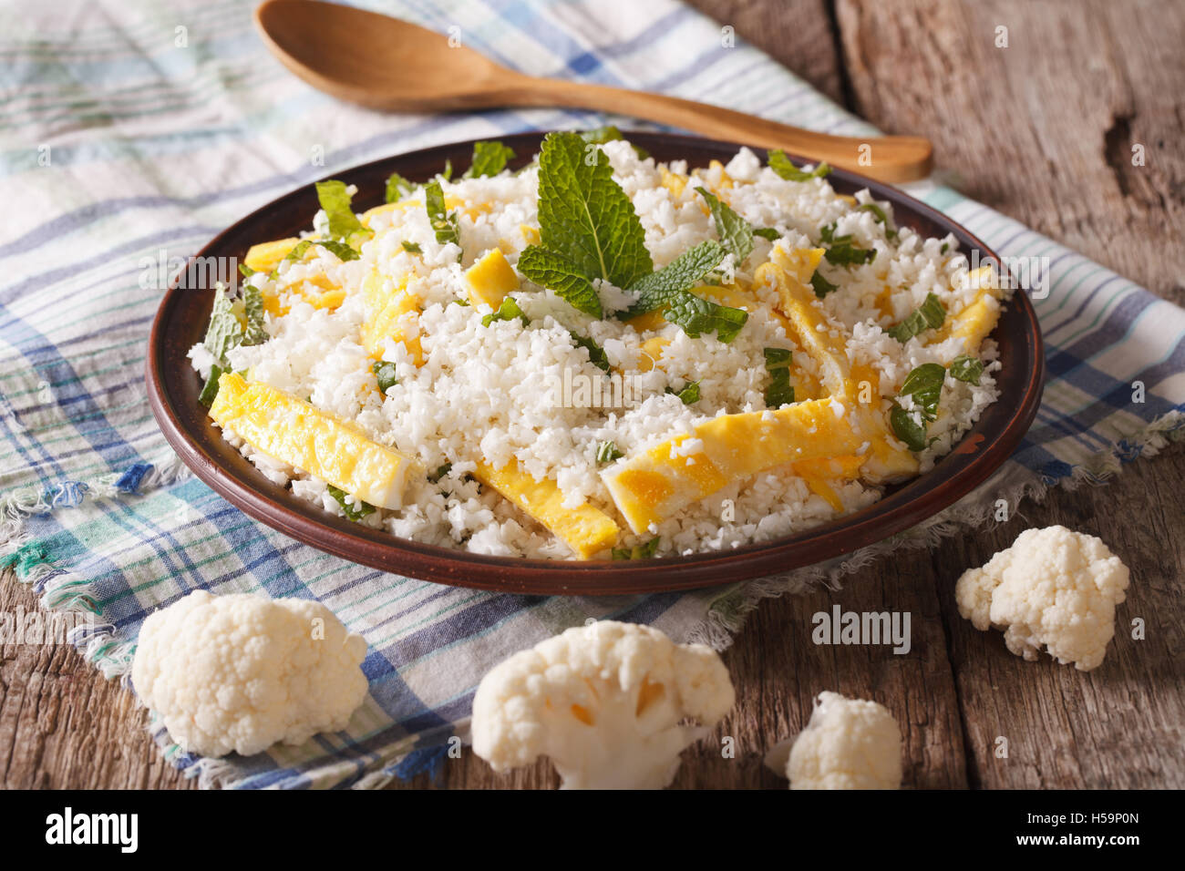 Dietary food: cauliflower rice with scrambled eggs and herbs closeup on a plate. horizontal Stock Photo