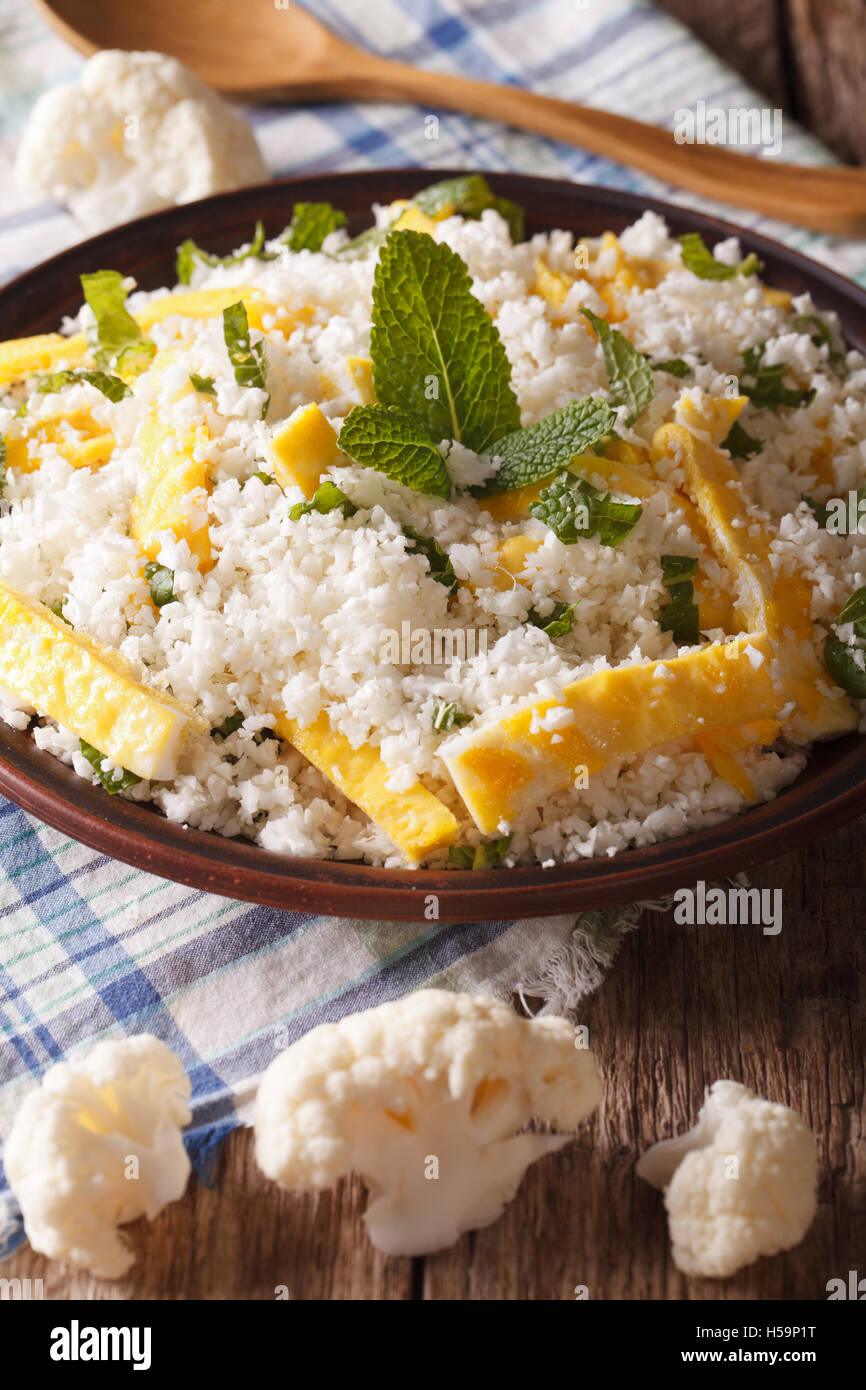 Cauliflower rice with egg and mint for paleo close-up on the table. Vertical Stock Photo