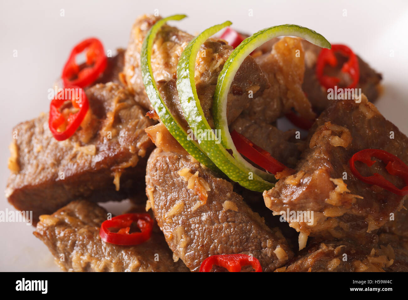 Beef rendang with coconut and spices macro on a plate. Horizontal Stock Photo