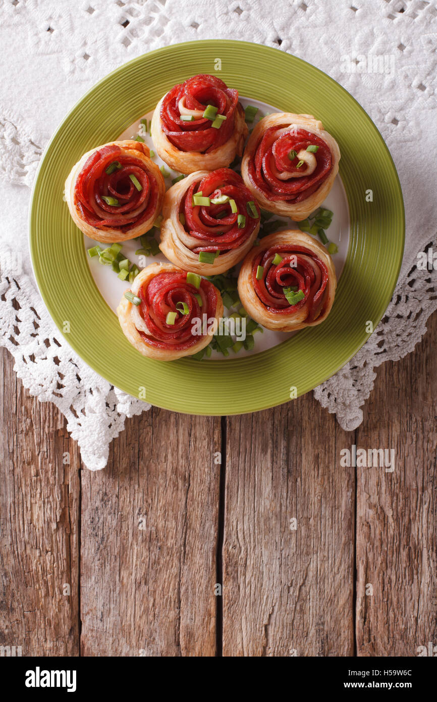 Baked rolls with salami in the form of roses on the table. Vertical top