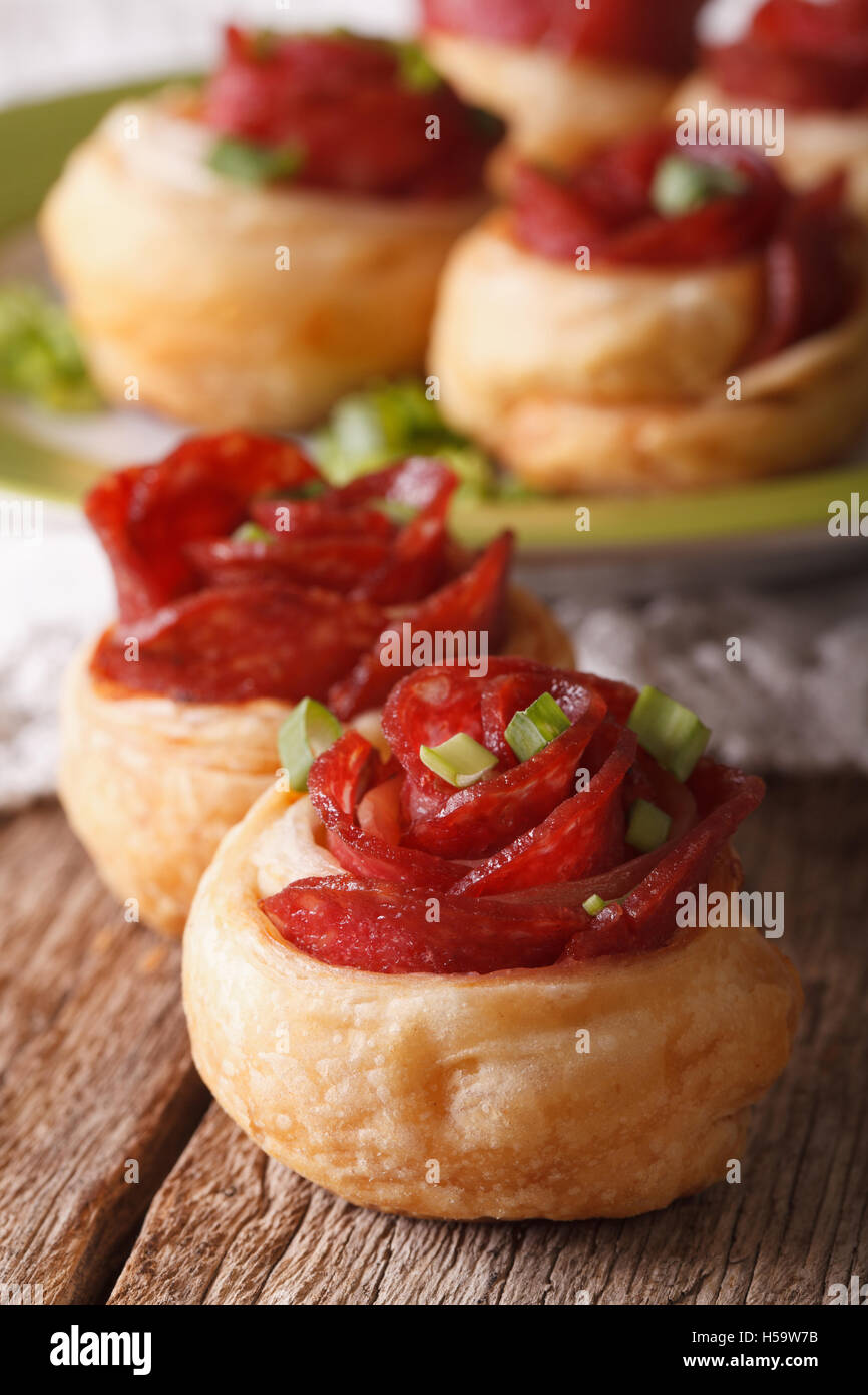 Baked rolls with salami in the form of roses on a table macro. Vertical