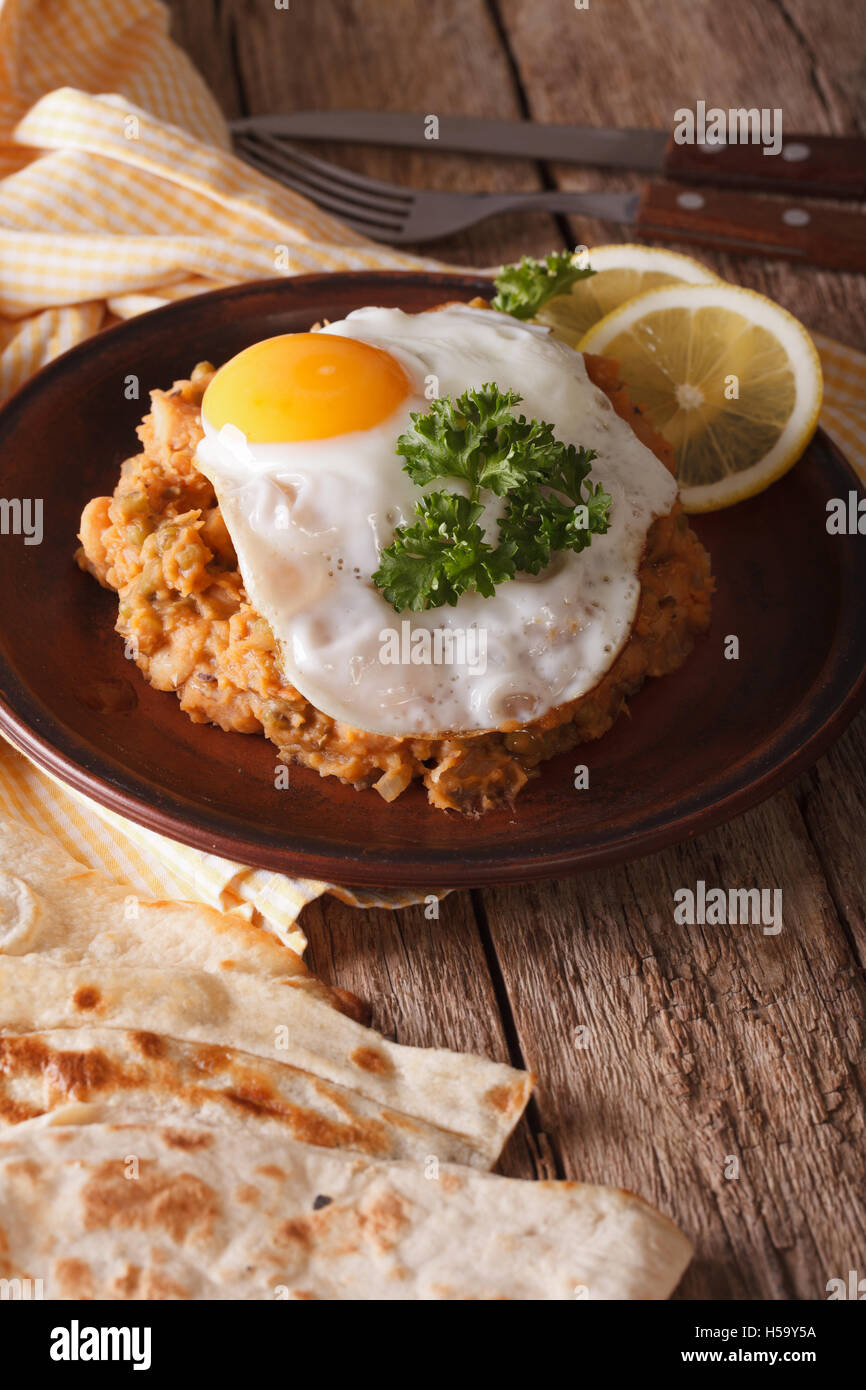 Arabic Breakfast: ful medames with a fried egg on a plate close-up. Vertical Stock Photo