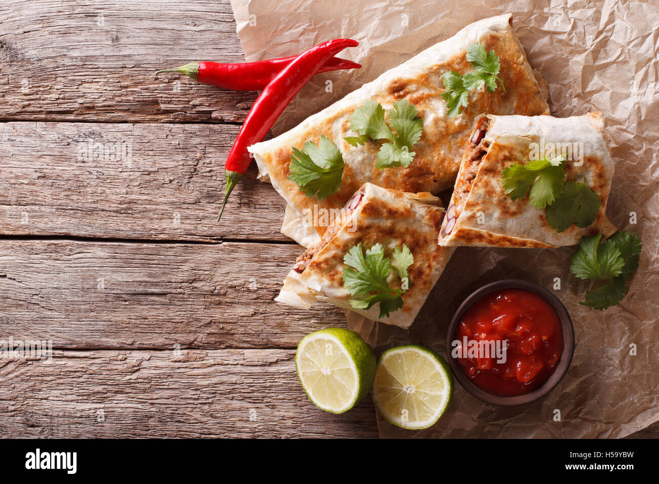 Mexican spicy chimichanga with meat and vegetables on the table. horizontal view from above Stock Photo