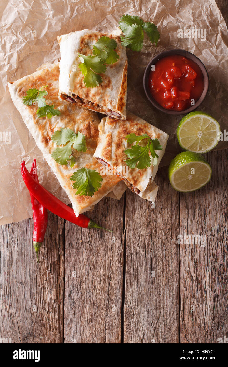 Mexican spicy chimichanga with meat and vegetables on the table. vertical view from above Stock Photo
