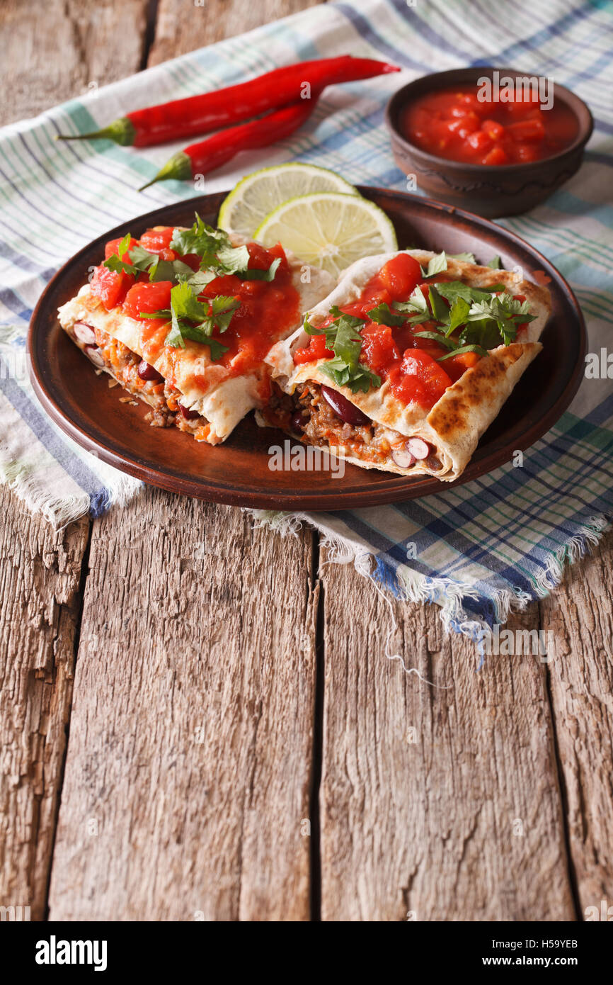 Mexican chimichanga with meat, vegetables and cheese on a plate close-up Vertical Stock Photo