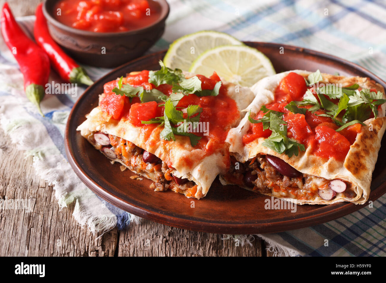 Mexican chimichanga with meat, vegetables and cheese on a plate close-up horizontal Stock Photo