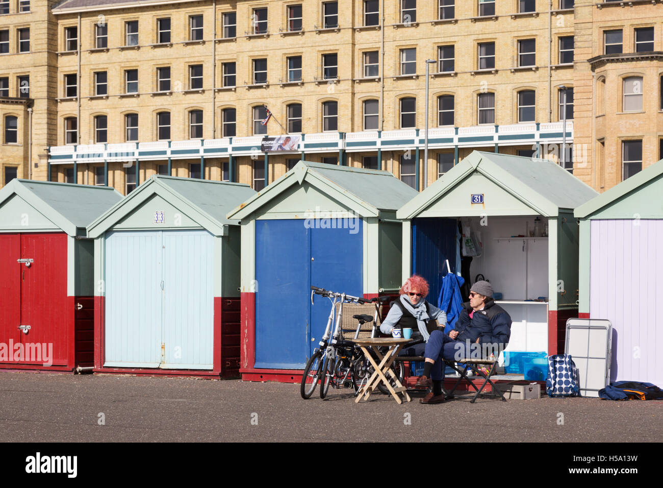 People sitting outside their beach hut, Brighton promenade, Brighton, East Sussex, England UK Stock Photo