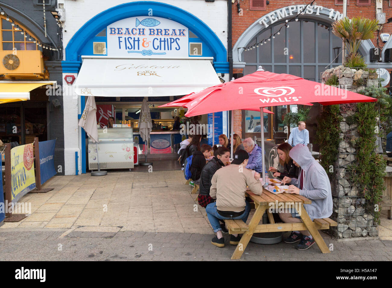 People eating fish & chips outdoors at a seafront cafe, Brighton Promenade, Brighton, East Sussex, England UK Stock Photo