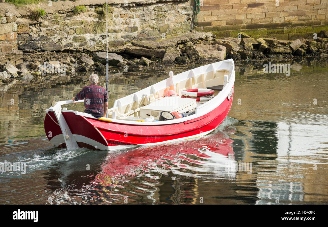 Fisherman heading out in Coble fishing boat at Staithes, North Yorkshire, England. UK Stock Photo