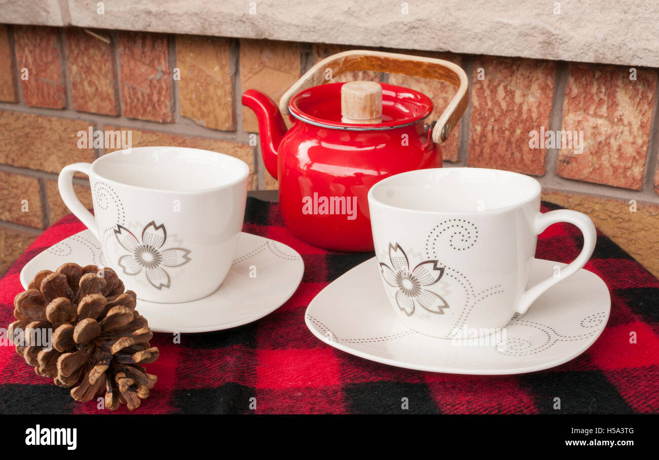 Elegant tea cups set for two with red teapot. Set outside on brick