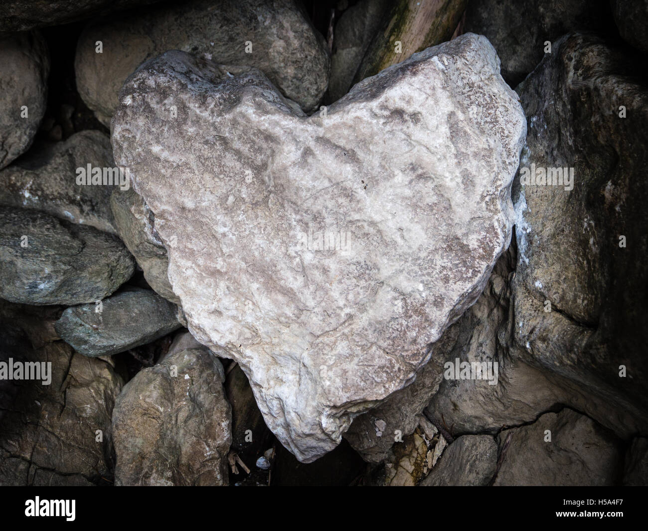 A stone naturally shaped as a heart, above other different stones. Stock Photo