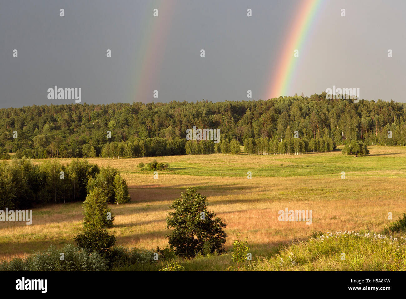 Bright primary and secondary rainbows over Gaujiena Valley in Latvia Stock Photo
