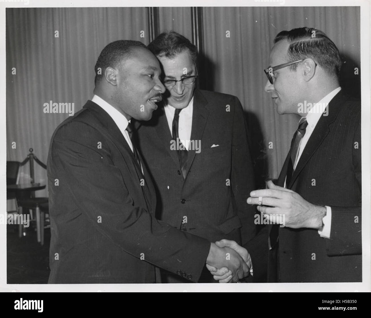 Martin Luther King, Jr. talking with Shad Polier while shaking hands with unidentified smoking man at American Jewish Congress fundraising event Stock Photo