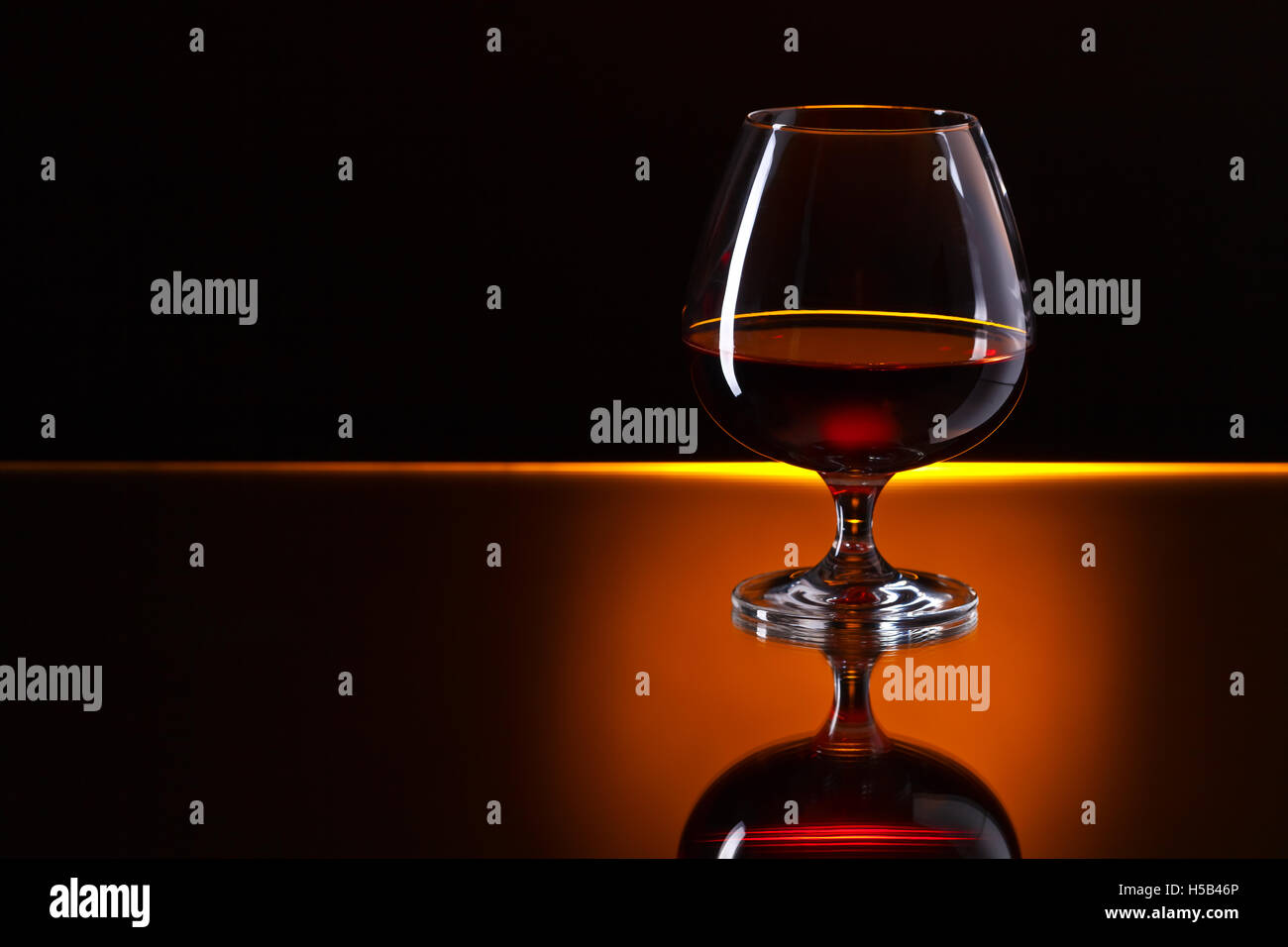 Snifter with brandy on a reflective background Stock Photo - Alamy