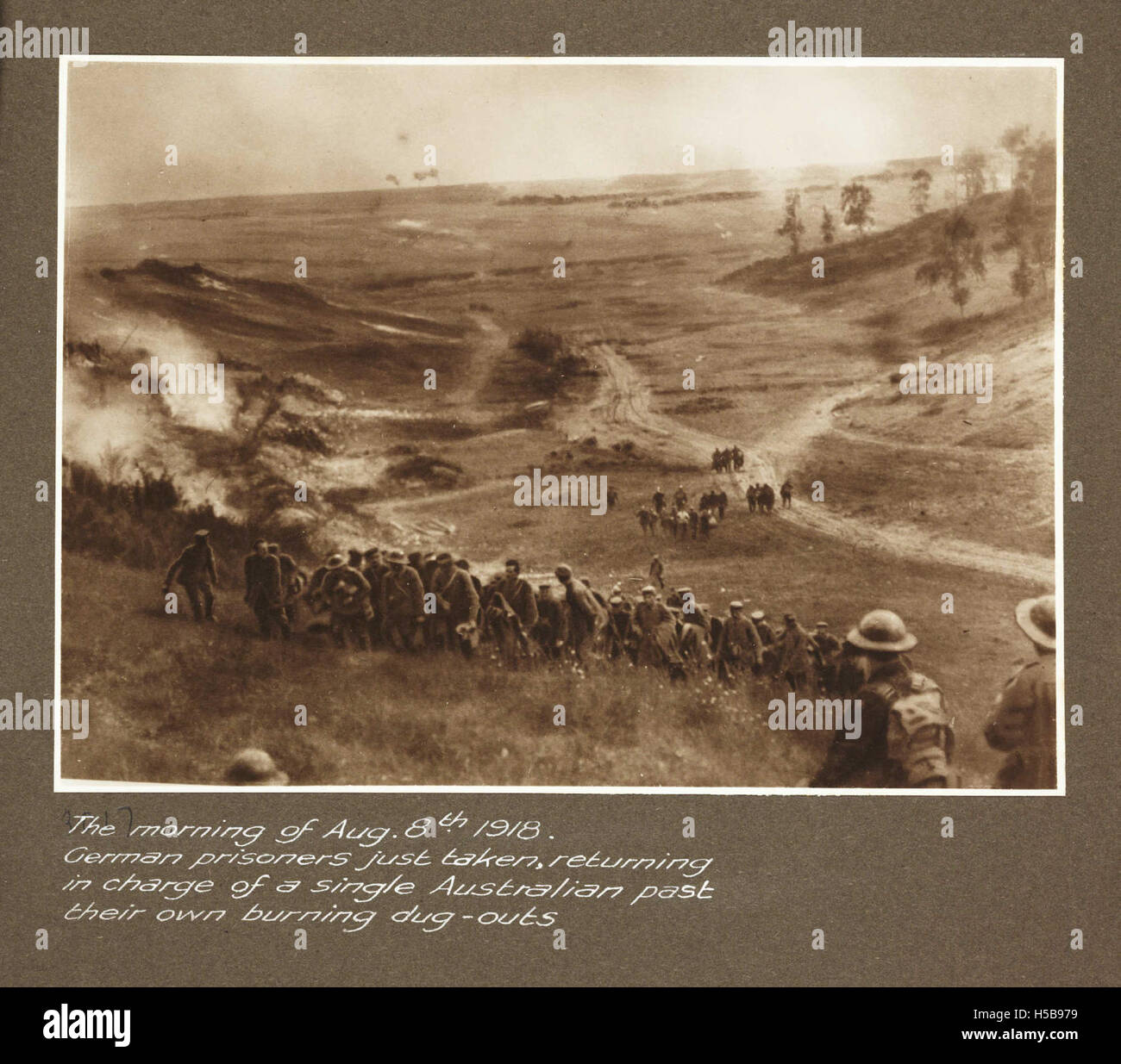 On August 8, 1918, German prisoners of war were escorted by a single Australian soldier past their own burning dug-outs, following the intense fighting of World War I during the Hundred Days Offensive. Stock Photo