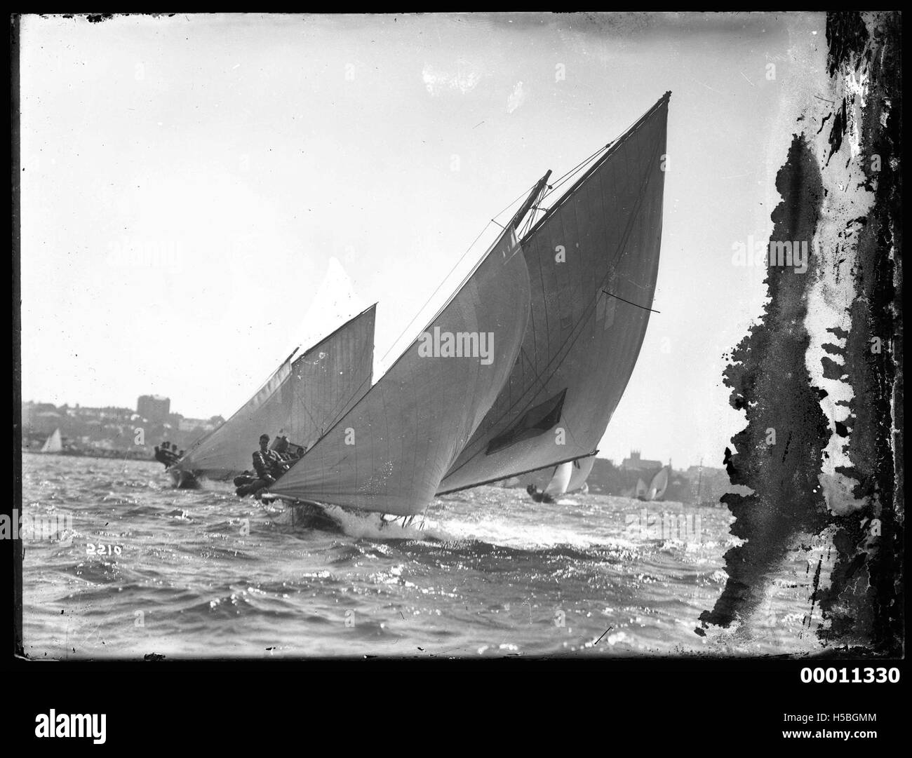 Photograph of sloops sailing on Sydney Harbour, with the Sydney Opera House and Sydney Harbour Bridge in the background, taken during a national festival. Stock Photo