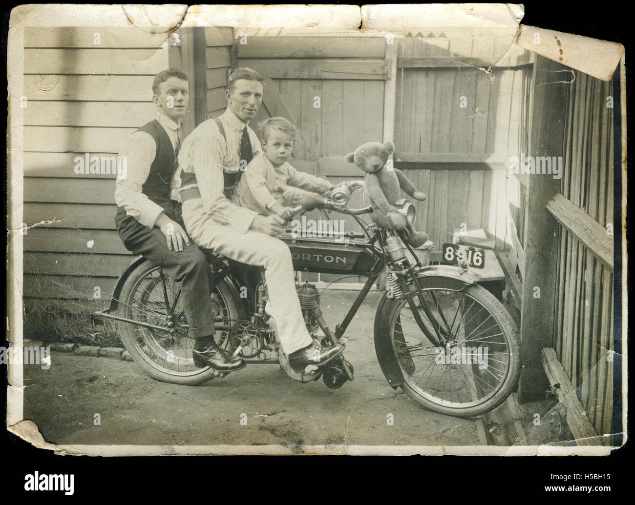 5 Two men and a young boy (Tom Wild) on a motorbike, with a teddy bear sitting on the handle bars Stock Photo