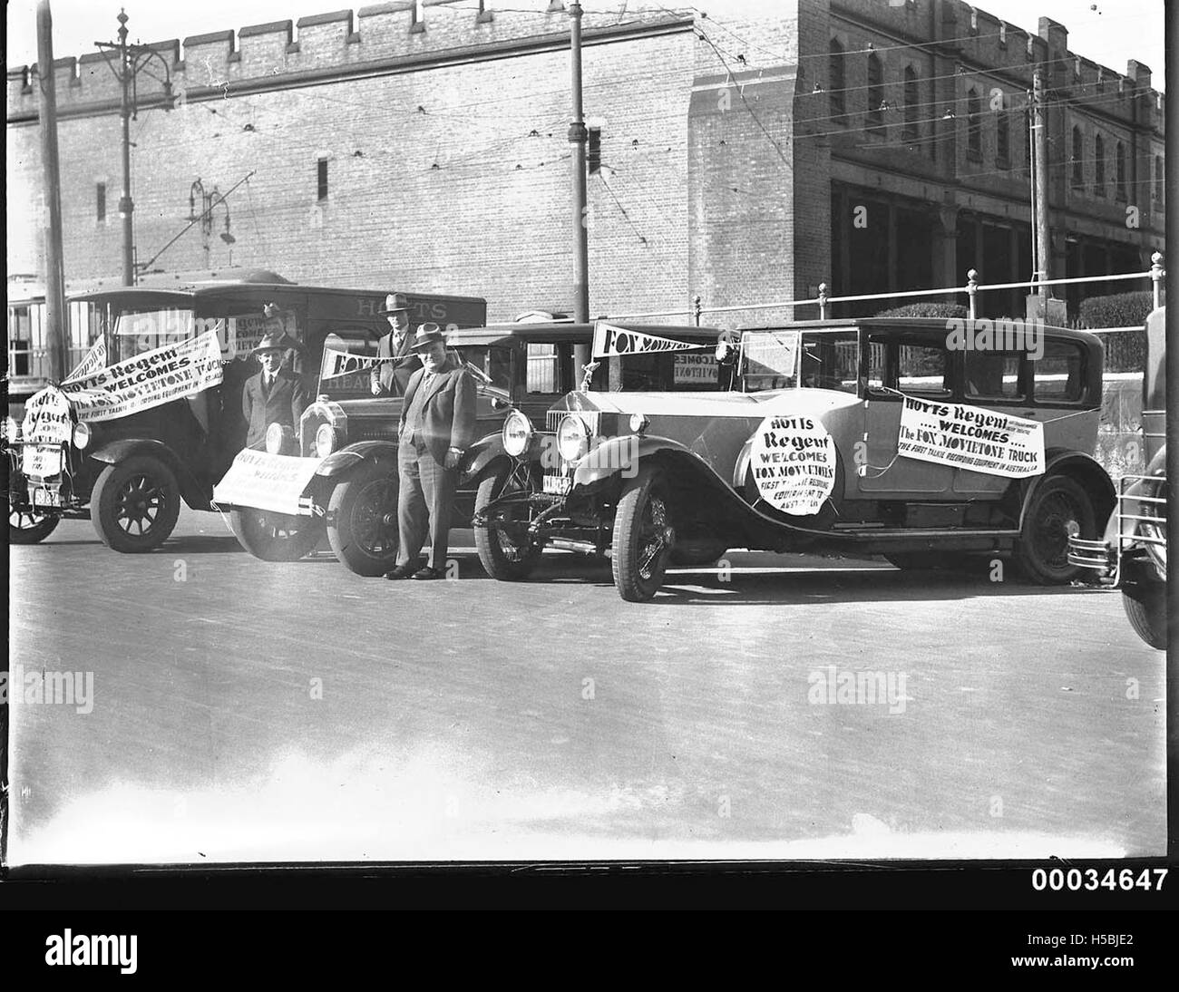 Four men posing near cars at a Movietone event Stock Photo