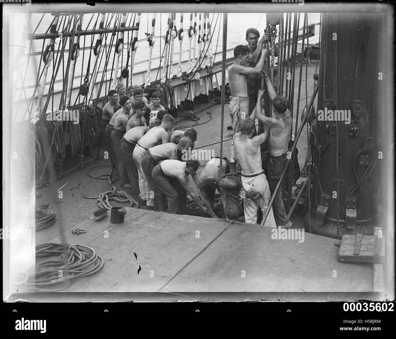Crew men pulling on a rope near a mast on board MAGDALENE VINNEN Stock Photo