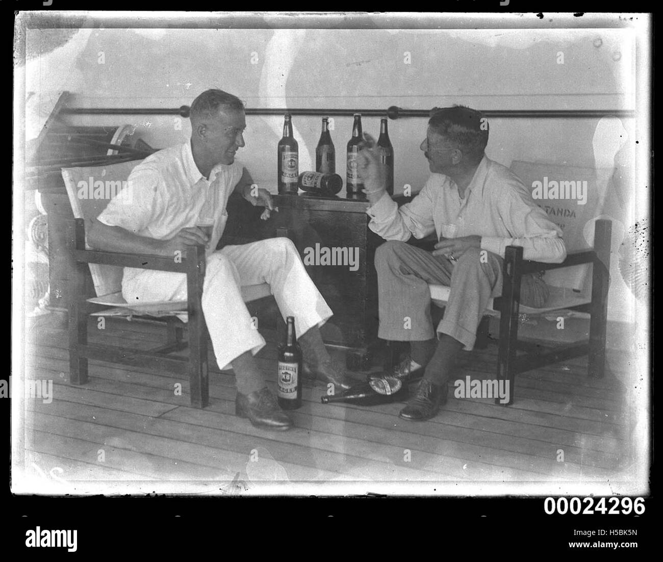 Two men seated, drinking beer and smoking cigars on board SS TANDA Stock Photo