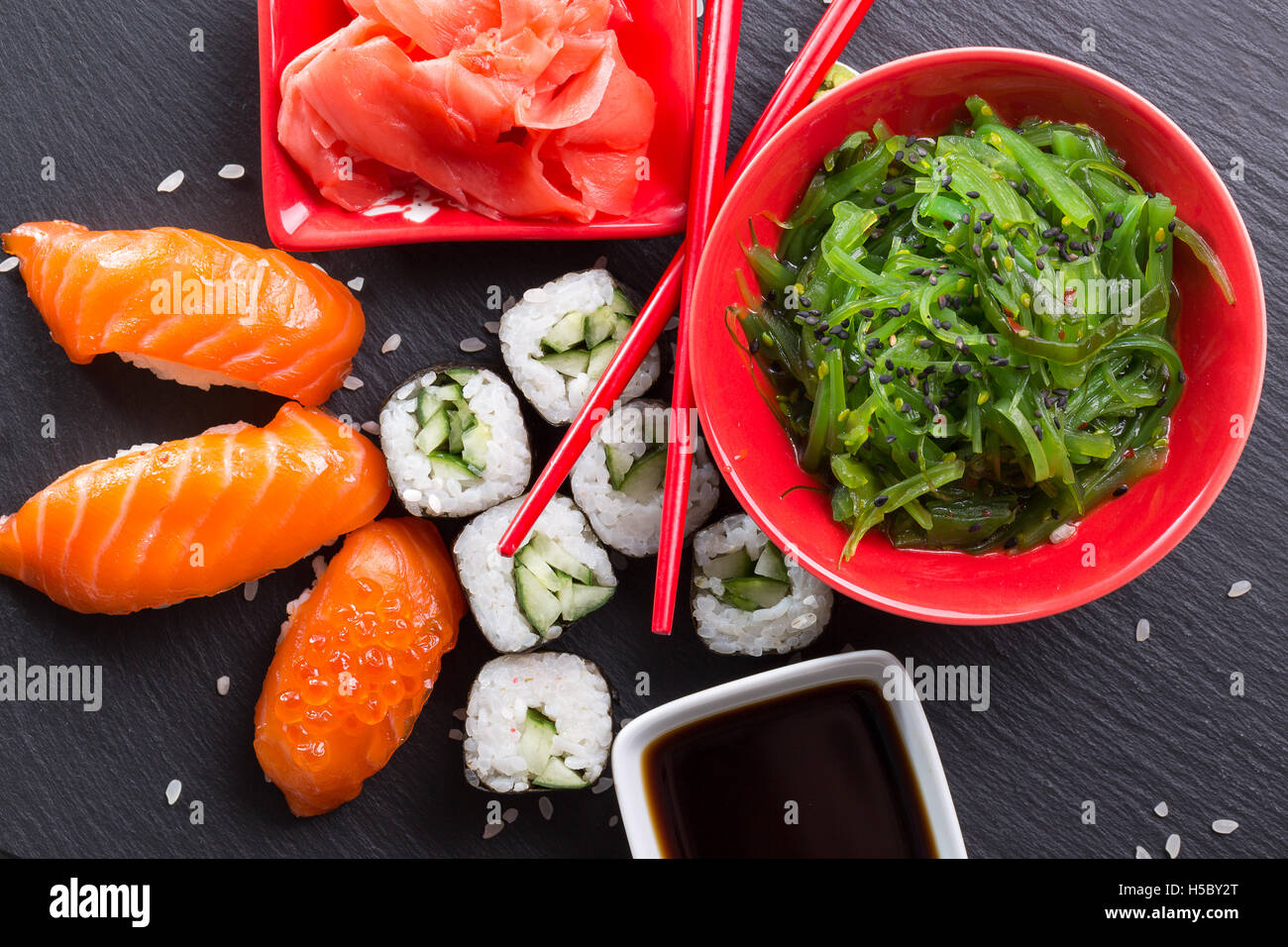 sushi and rolls with green salad on slate table. Stock Photo