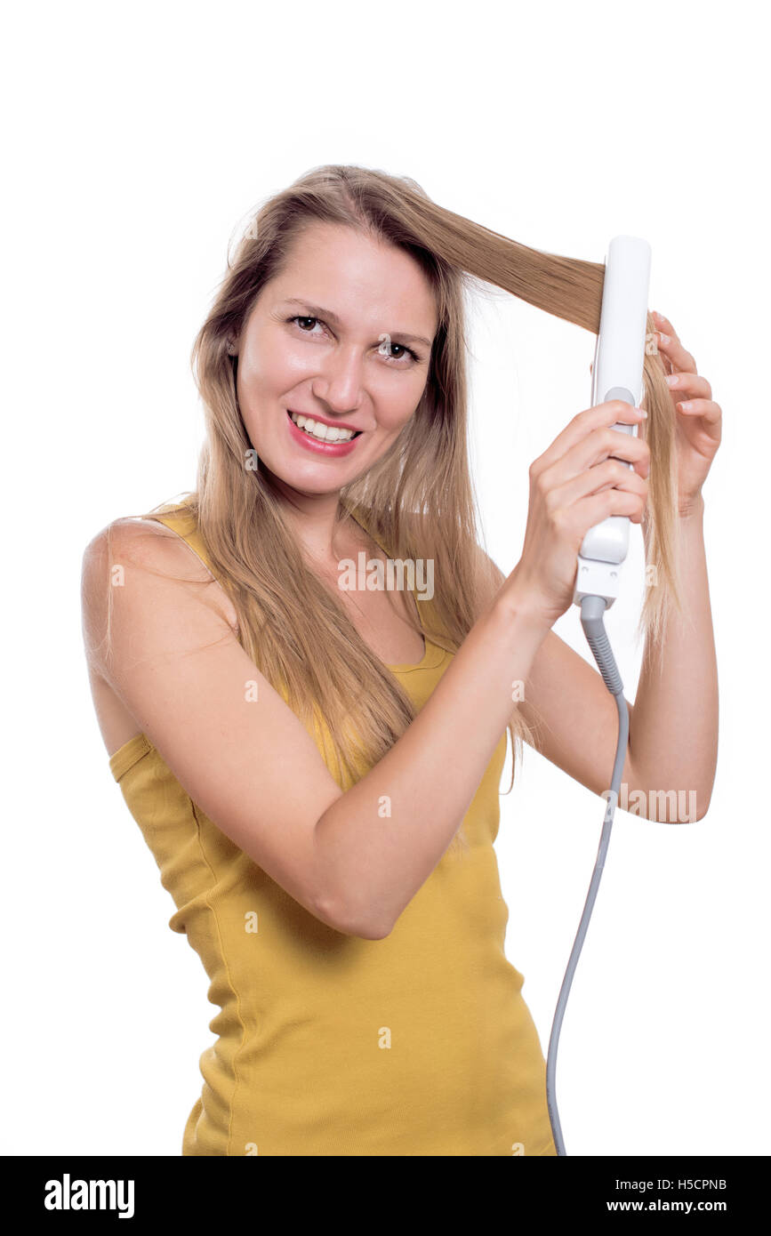 Young woman straightening her hair using hair straightener Stock Photo