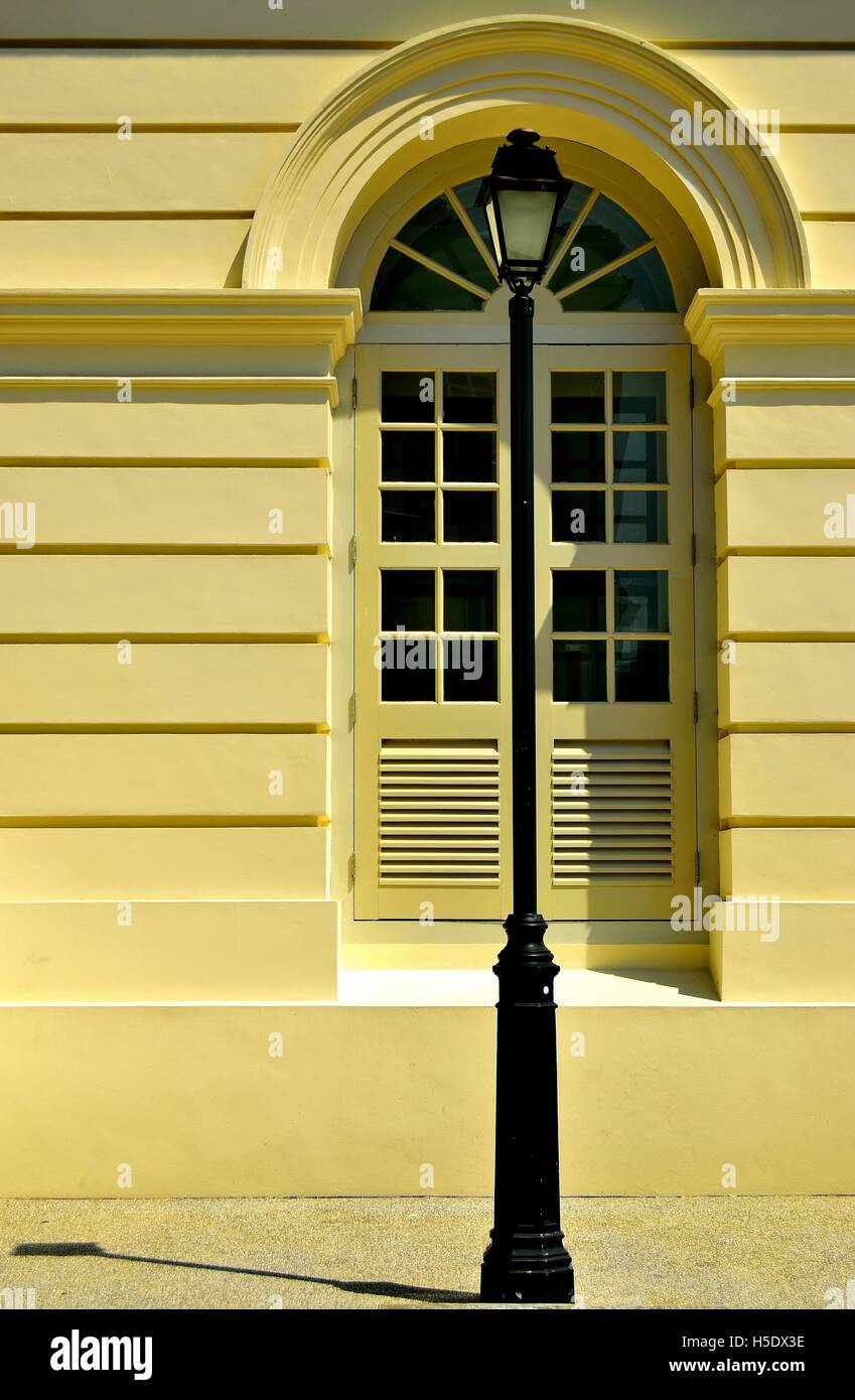Vintage Victorian lamp post in front of an antique arched window in the