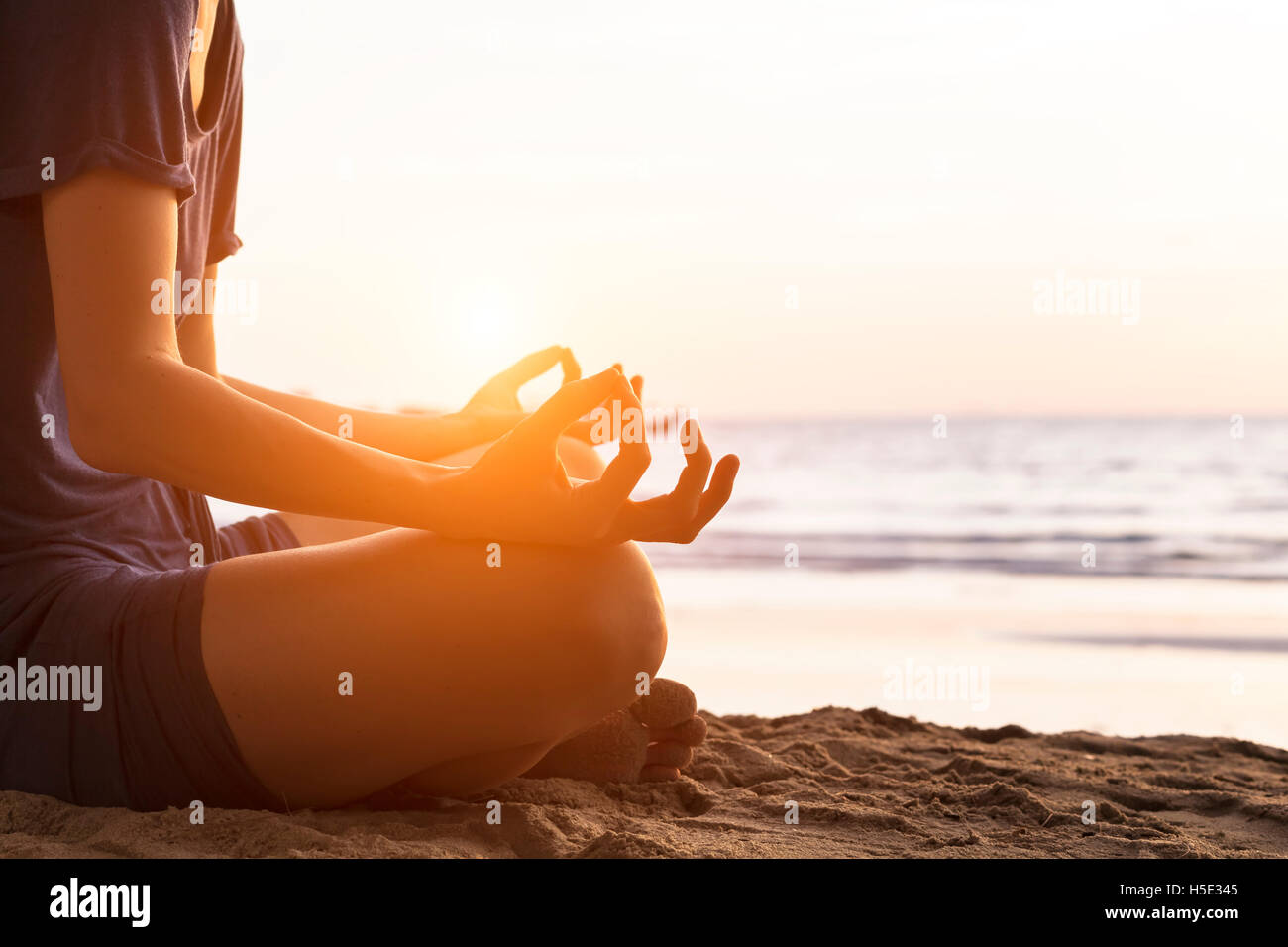 Girl relaxing with yoga on the beach at sunrise, gyan mudra Stock Photo