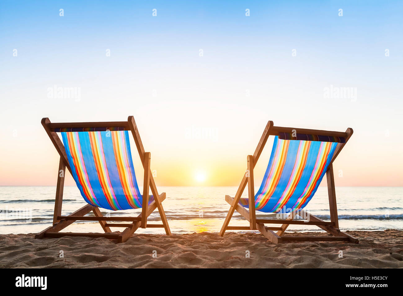 Two deck chairs on a tropical sandy beach with beautiful colorful sunset Stock Photo