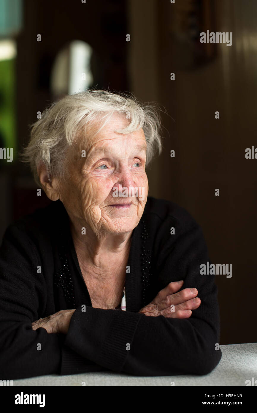 An elderly woman sitting at the table. Stock Photo