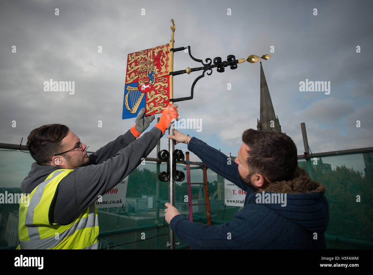 Stonemason's fix a restored weathervane to the top of the Market Cross