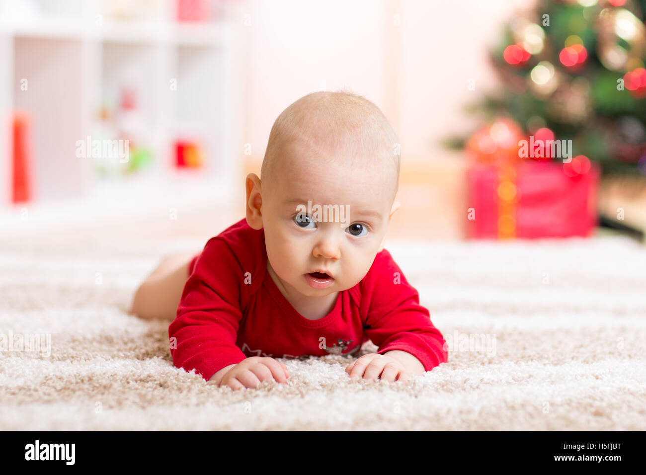 Cute baby boy lying on tummy in front of Christmas tree Stock Photo