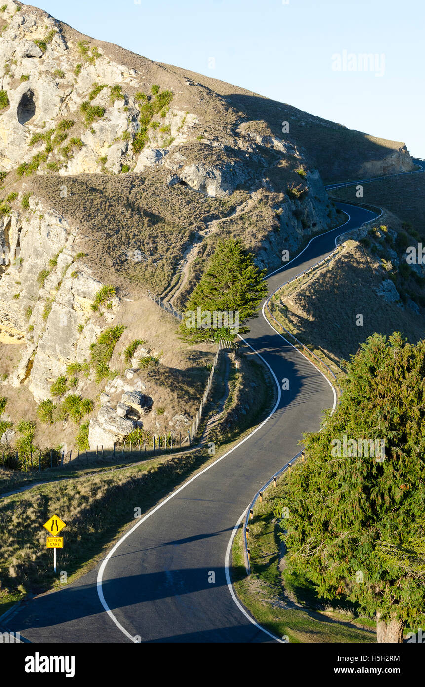 Winding road with 'road narrows' and 'extreme care' road signs, Te Mata Peak, Hastings, Hawke Bay, North Island, New Zealand Stock Photo