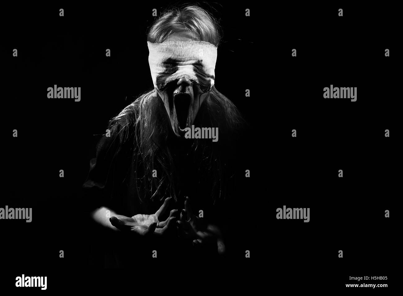 scared bloody girl screaming on black background with copyspace, monochrome Stock Photo