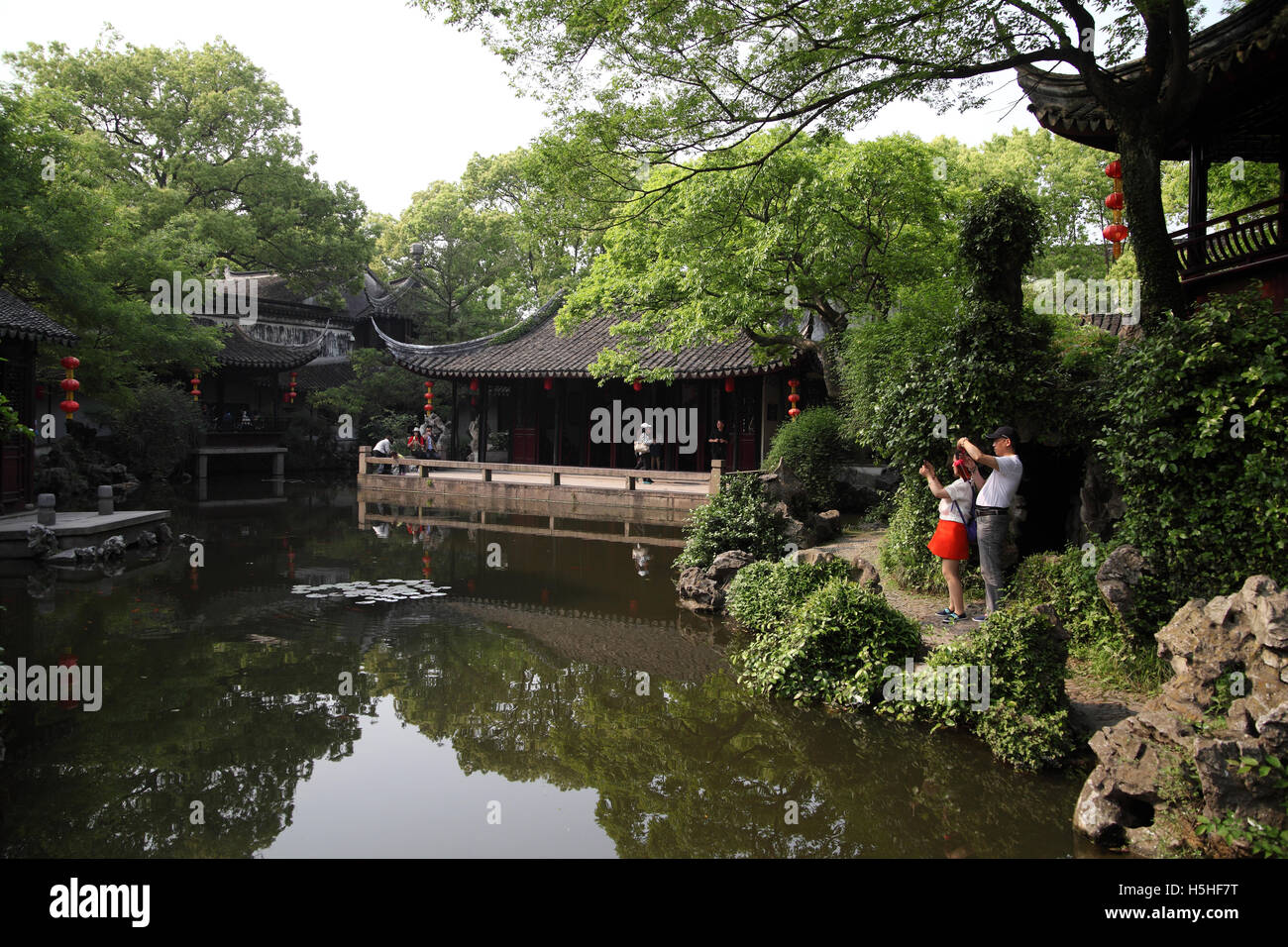 Chinese tourists use their smartphones to photograph the Tuisi Garden, a classical Chinese garden built in 1885. Tongli, China. Stock Photo