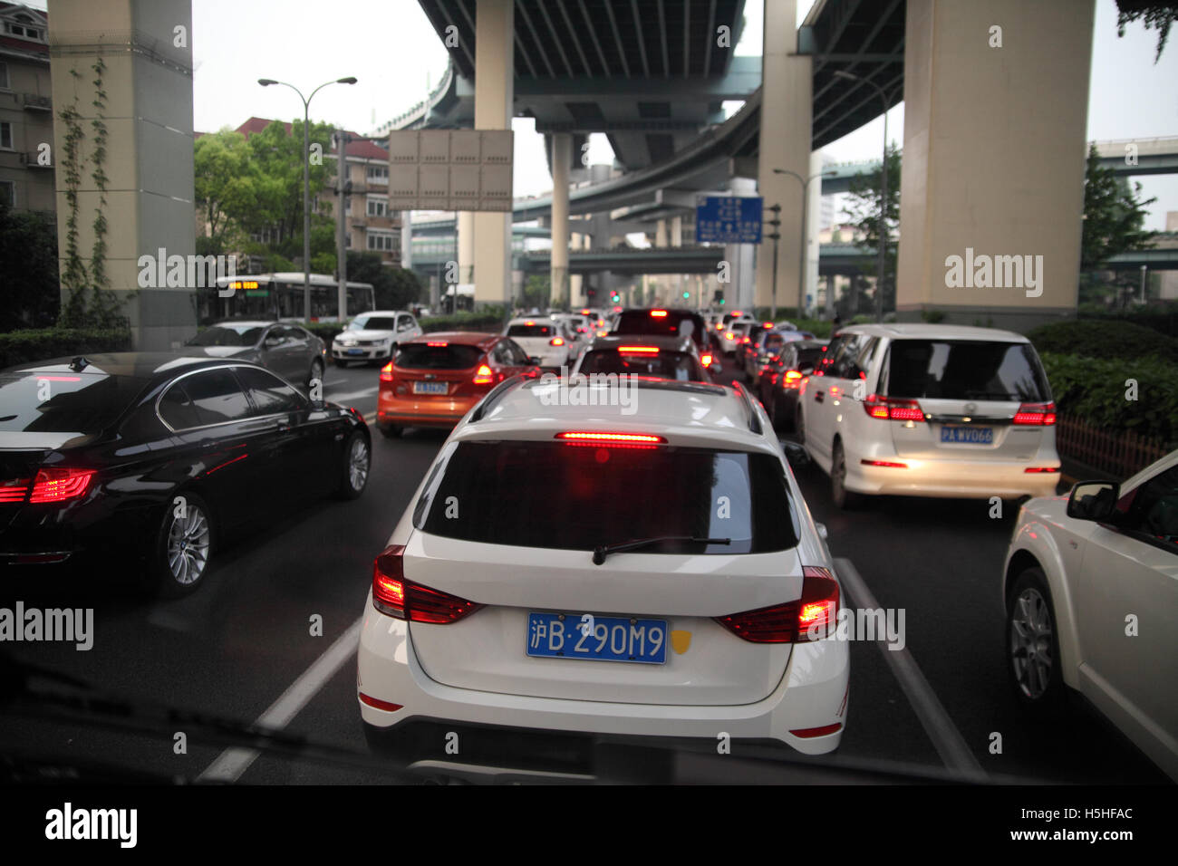 Heavy traffic, lots of modern cars, a traffic jam in the late afternoon, one also sees the second level highway above. Shanghai. Stock Photo