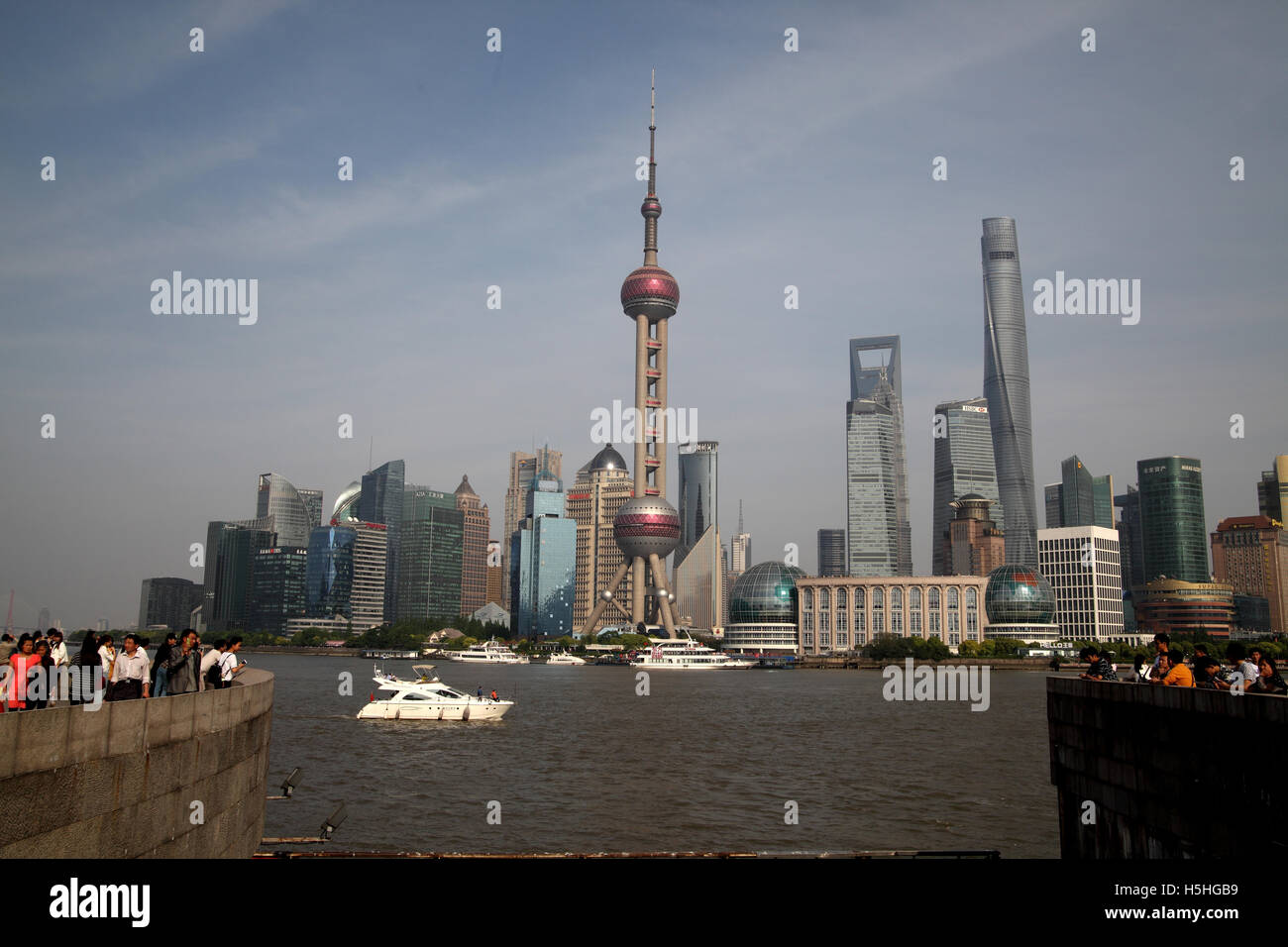 Tourists stand on the Bund Promenade, look at Pudong, the Financial district also called Lujiazui skyline and the Huangpu River. Stock Photo