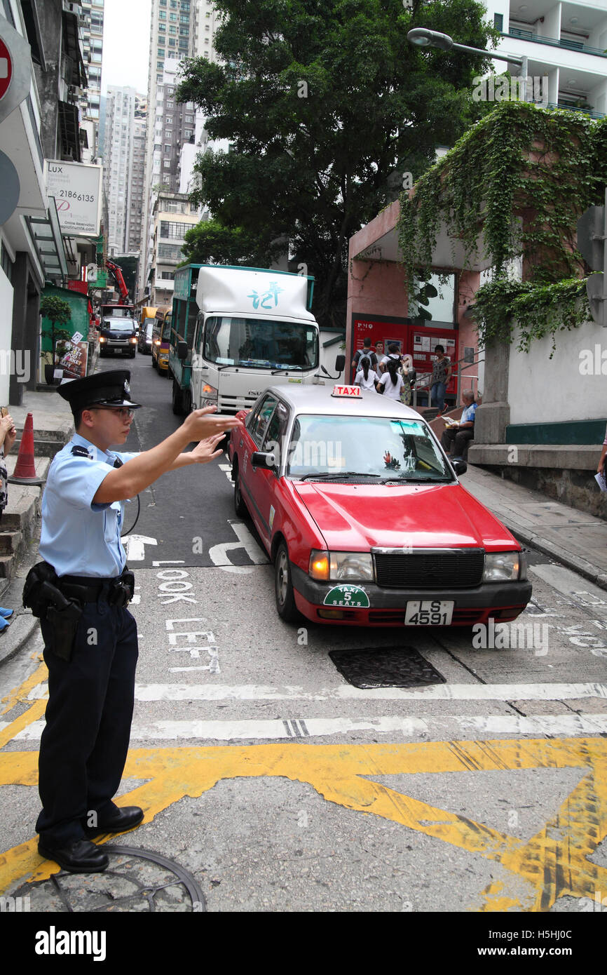 A Chinese policeman directing traffic gesturing cars to stop and wait or go forward Hong Kong, Hong Kong. 06.05.2016 Stock Photo