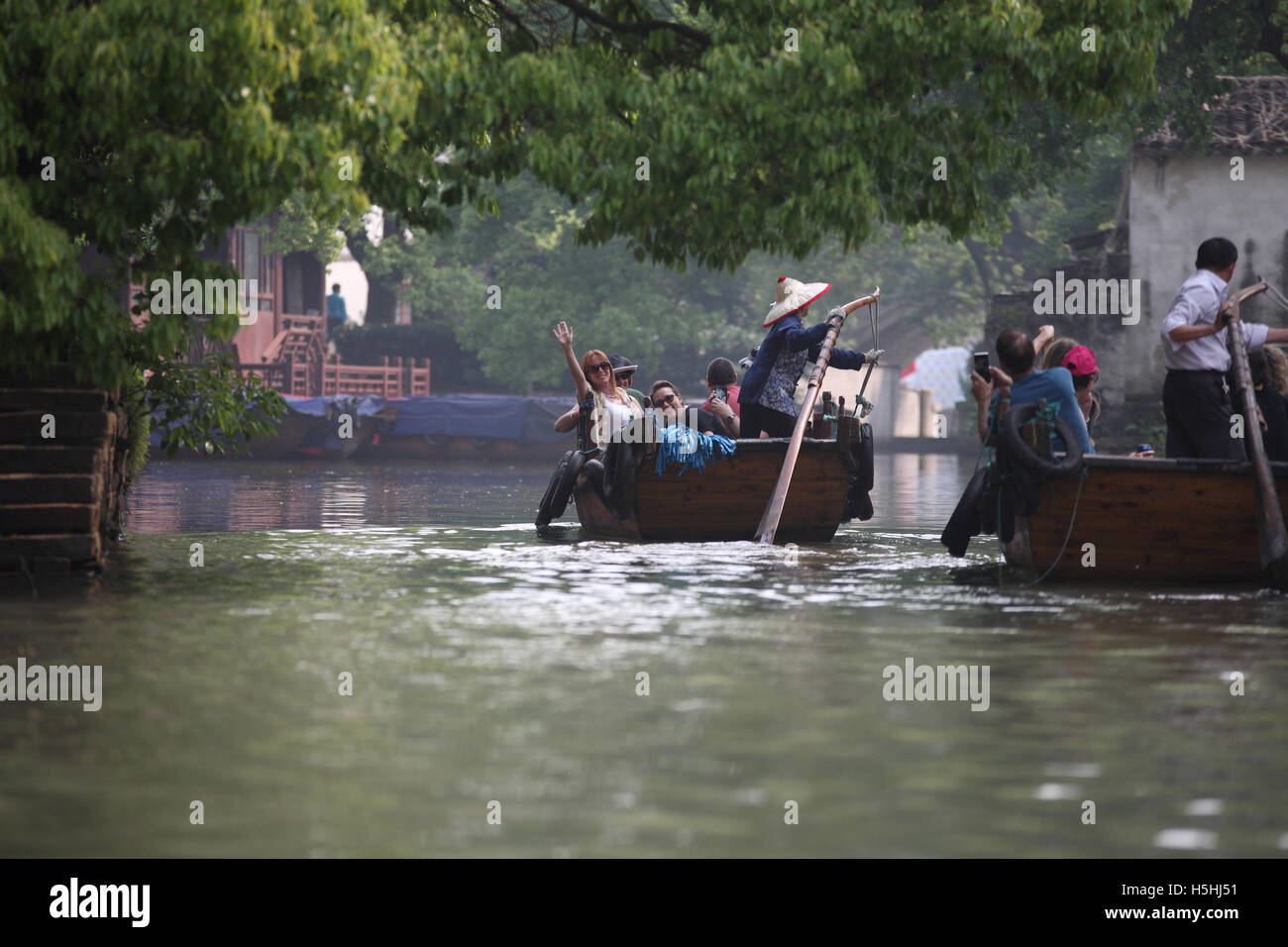 Israeli tourists ride boats in a Tongli canal, an old Chinese town near Suzhou, in one of the boats a woman is rowing, in the other a man. China. Stock Photo