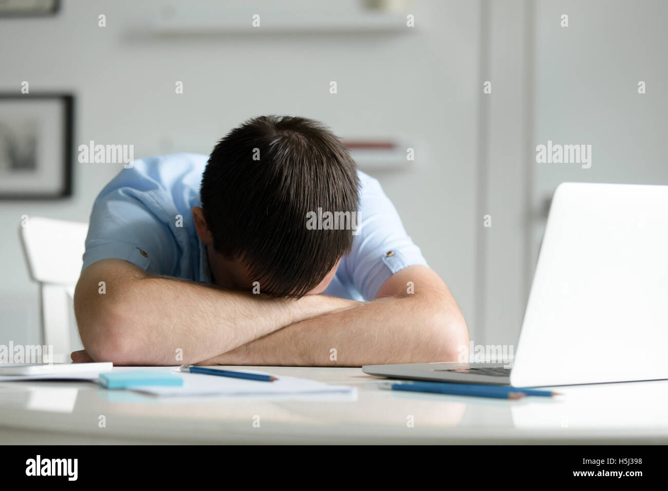 Portrait of a man lying down at desk near laptop Stock Photo