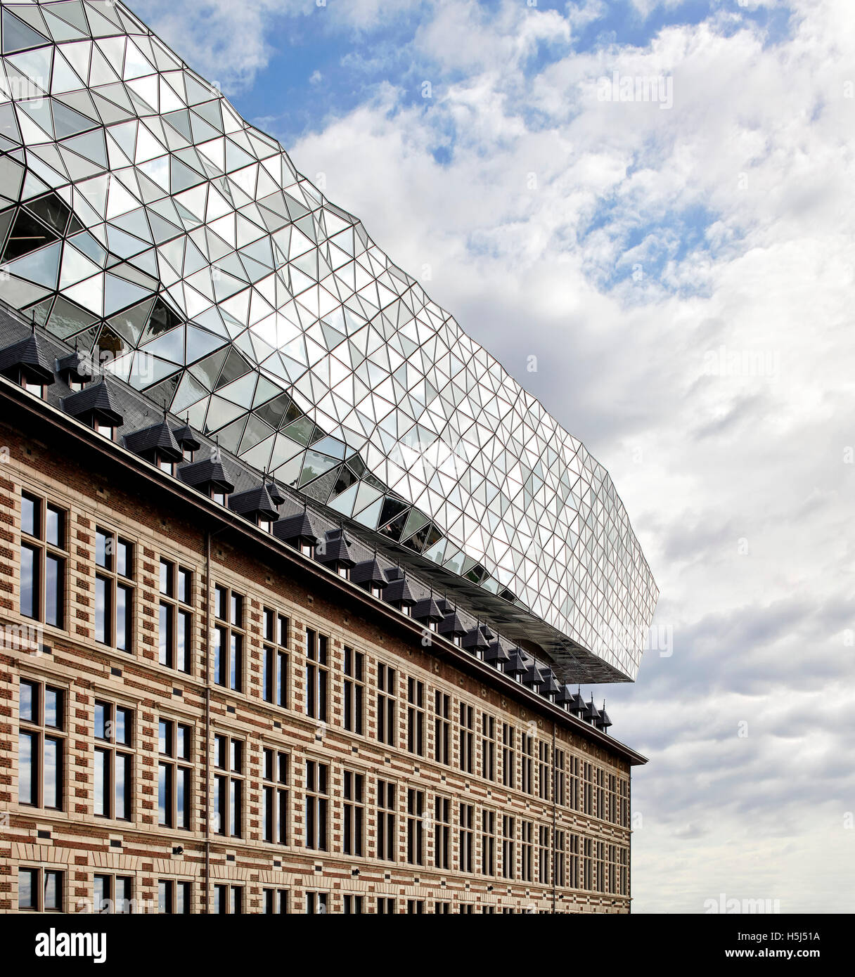 Facade of old fire station and floating glazed volume in perspective. Port House, Antwerp, Belgium. Architect: Zaha Hadid Architects, 2016. Stock Photo