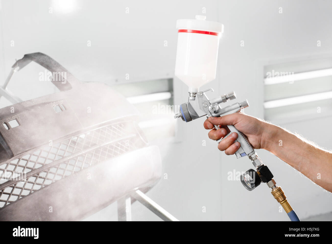 worker painting a car black blank parts in special garage, wearing