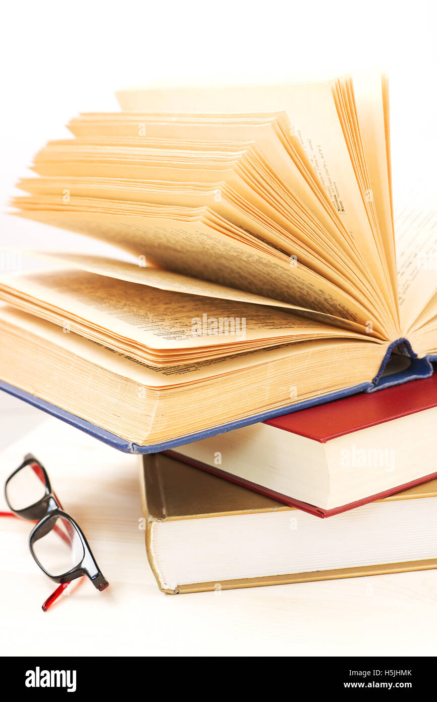 Open dictionary, thick books and eyeglasses Stock Photo