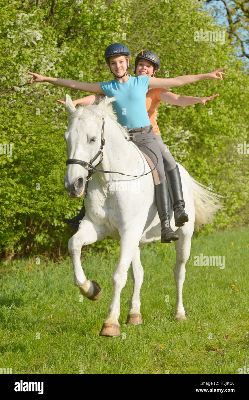 Two young riders riding bareback together on a Bavarian horse cantering