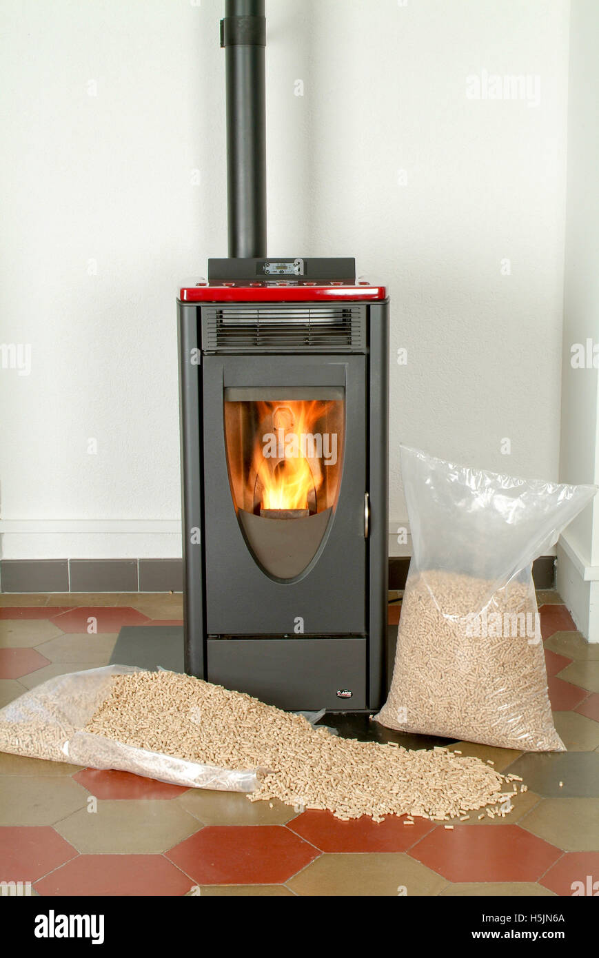 Modern domestic pellet stove with a burning flame and bags full of particle pellets Stock Photo
