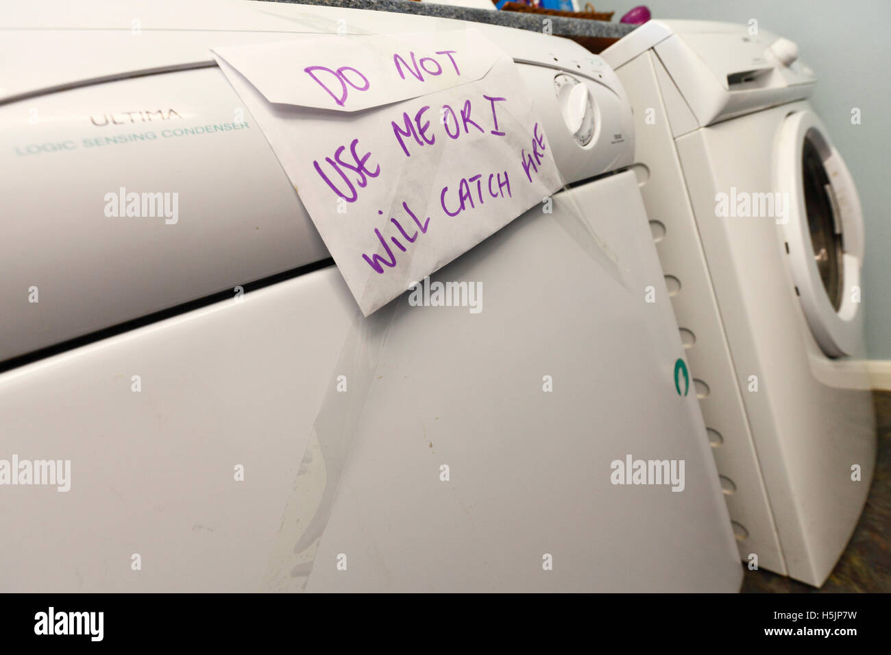 Faulty tumble drier with a warning sign not to use. Stock Photo