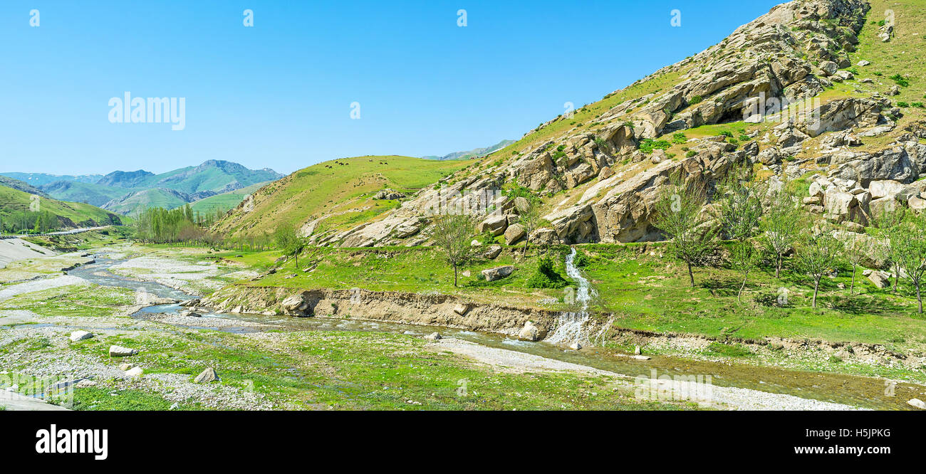 The narrow twisted river flows along the rocky valley between Zarafshan and Gissar mountain ranges of Pamir-Alay, the cows graze Stock Photo