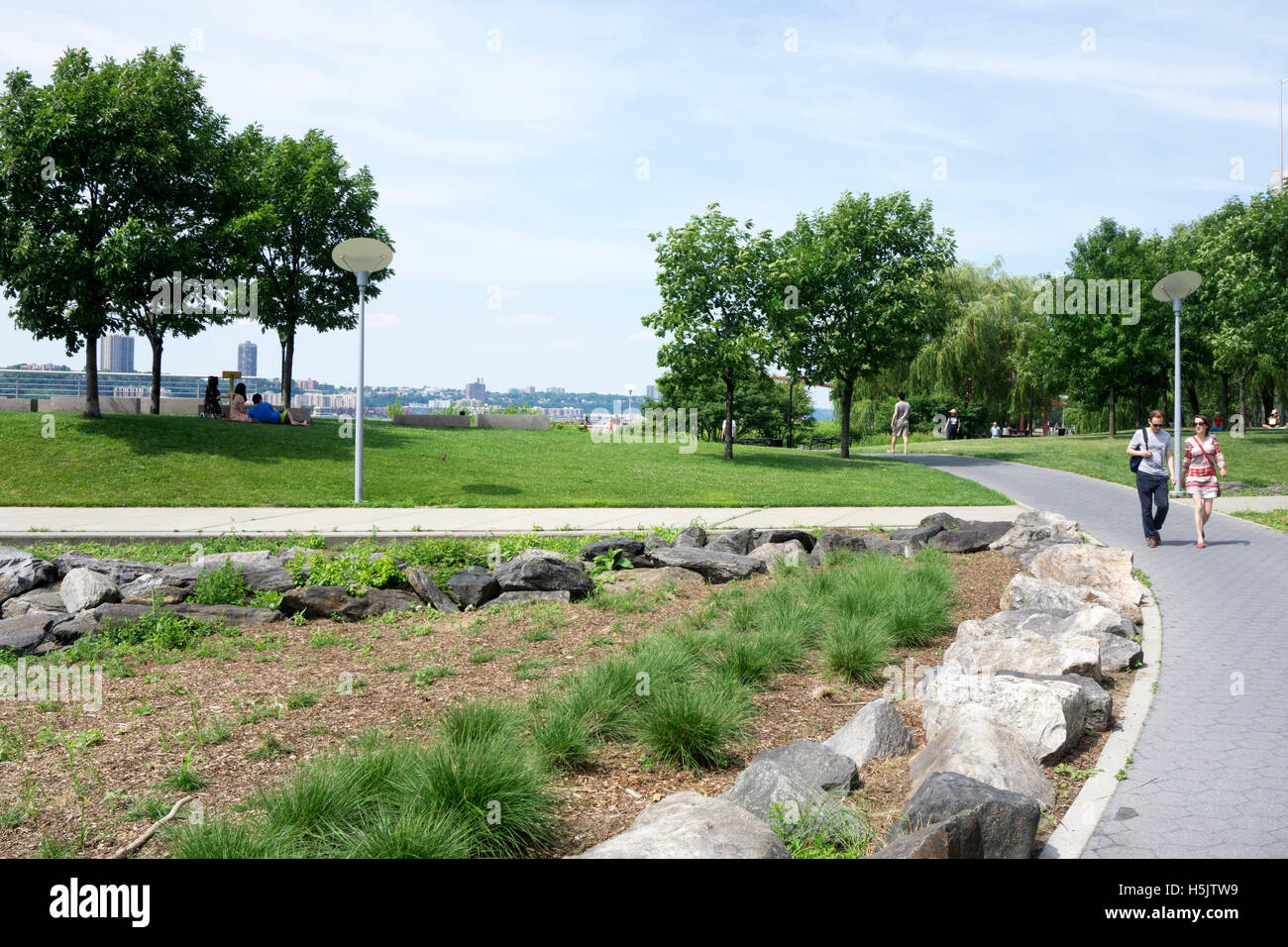 Riverside park is inviting prospect on glorious sunny July 4 4th with people strolling sunning or picnicking with river view Stock Photo