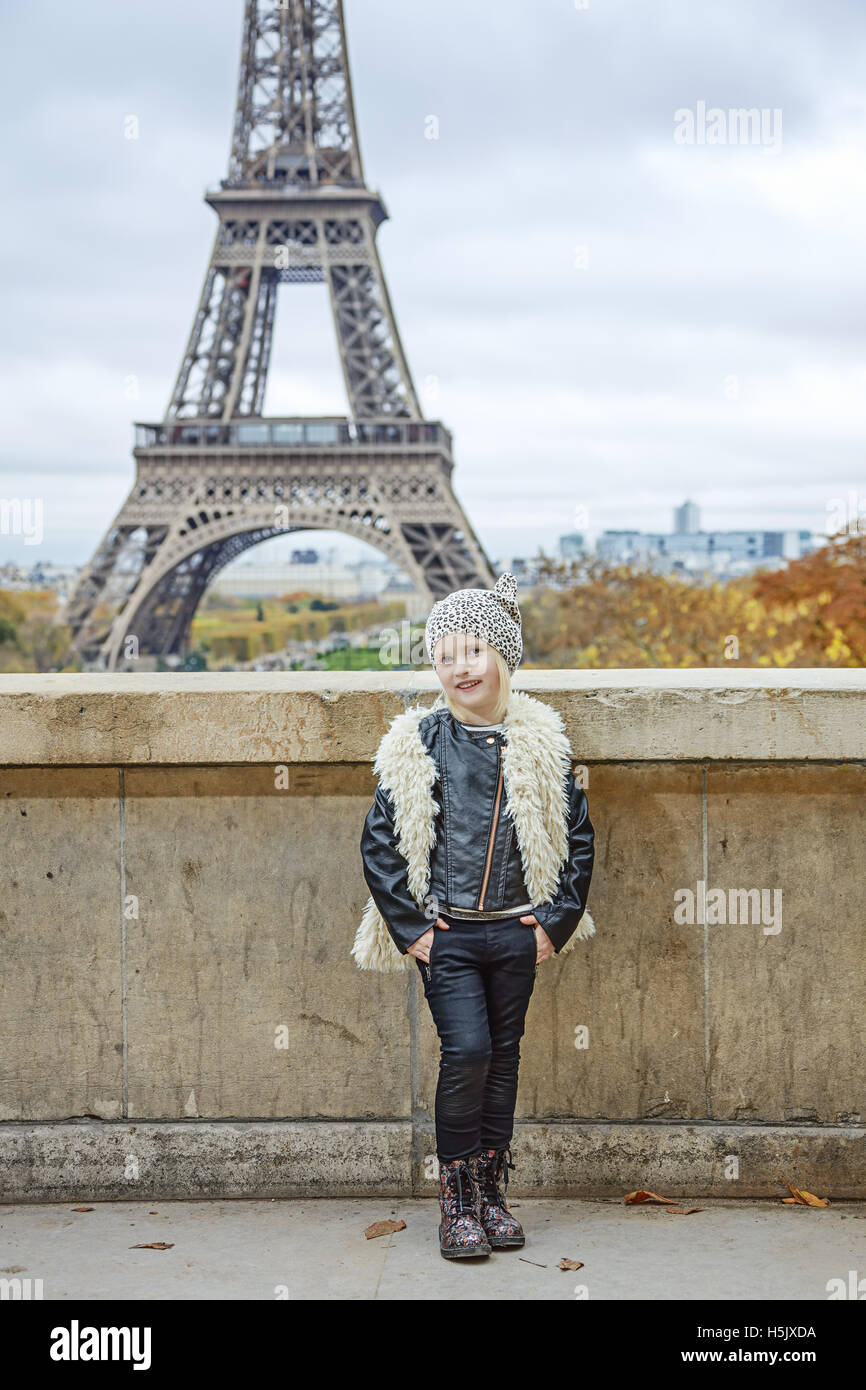 Bold Winter in Paris. Full length portrait of smiling trendy child in the front of Eiffel tower in Paris, France Stock Photo