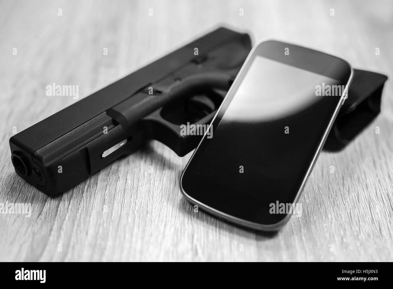 A gun and a modern smart phone, black and white Stock Photo